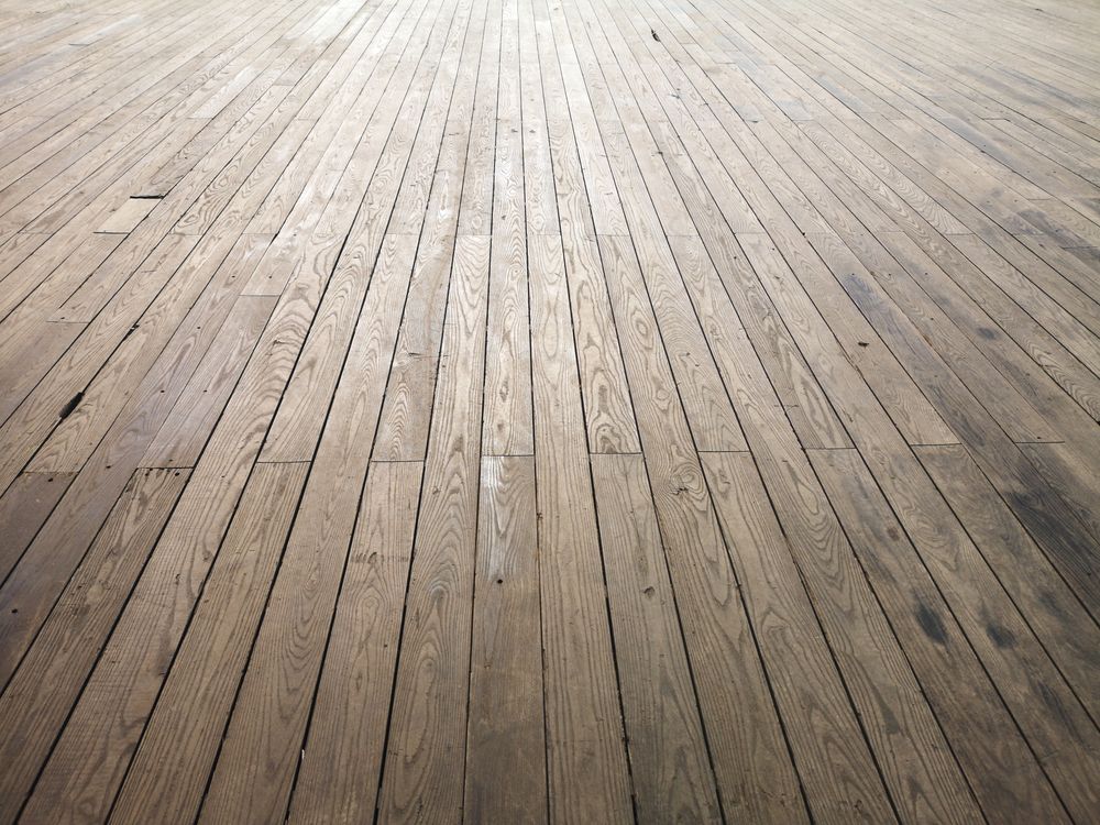 Sanding an old hardwood floor back to bare wood.